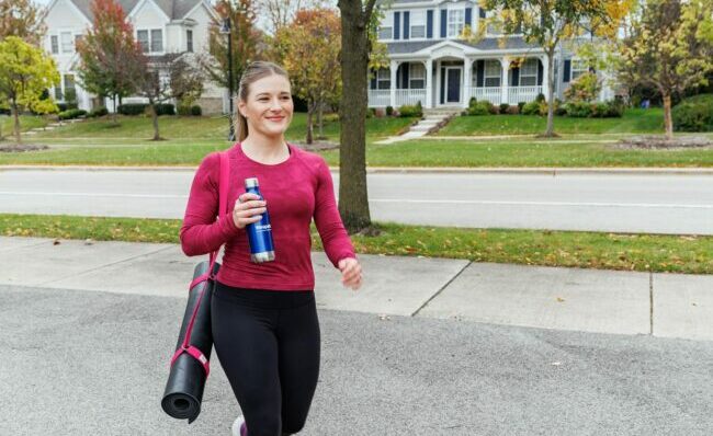 A woman with yoga gear walking outside