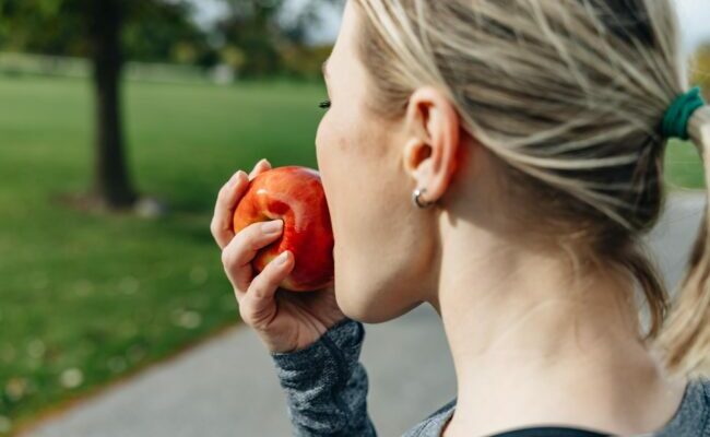 A woman eating an apple outside