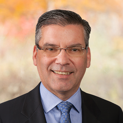 A portrait of Robert Christophel. He's wearing eyeglasses, a suit and tie, and he's smiling.