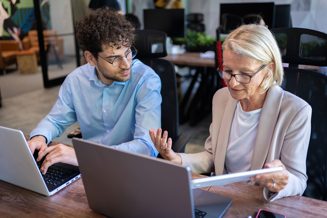 Man and elderly woman talking at their computers