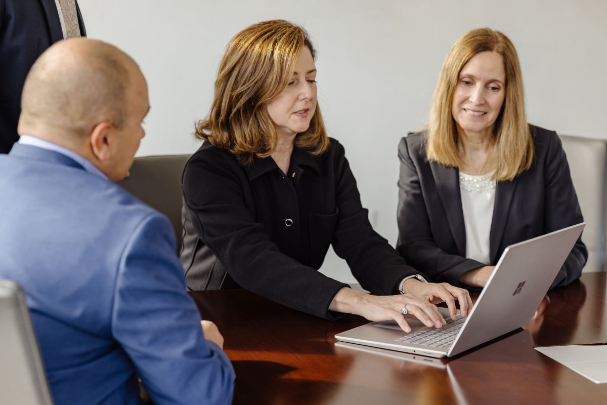 Three members of the investment teams collaborating at a table with a laptop.