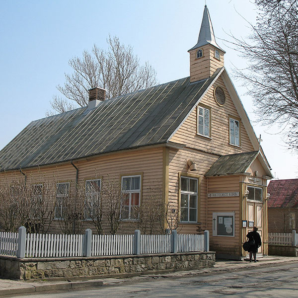 The outside of a brick church with a white picket fence.